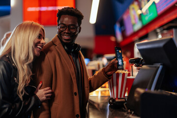 Couple paying with mobile app in theater.