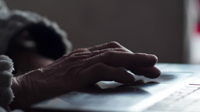 close-up of the hand of an old man using a laptop. selective focus. the concept of a pensioner using a computer for social networks, work and entertainment at home