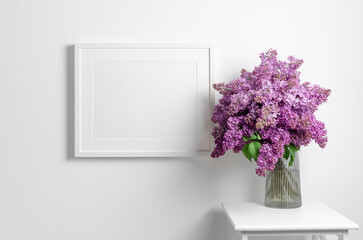 Landscape frame mockup on white wall with lilac flowers, blank mockup template with copy space