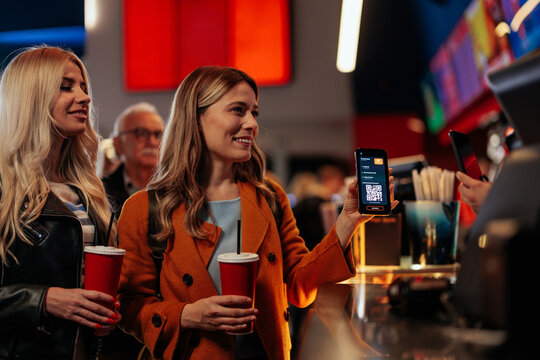 Female friends at cash register in cinema.