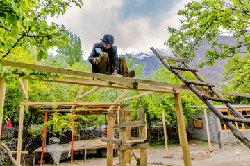 Carpenter creating a wooden structure for new cottage at at mountain resort with the view of snow...