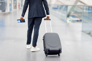 Unrecognizable Black Man Wearing Suit Walking With Suitcase At Airport