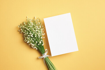 Blank paper card mockup with lily of the valley flowers on yellow background