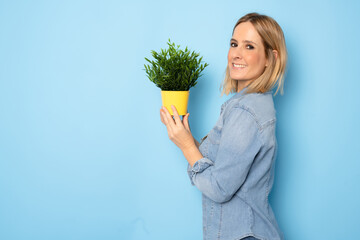 Smiling happy woman holding green indoor plant. Potted plant market concept.