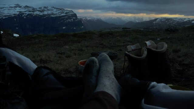Person without shoes camping on Trolltunga, motion back view to tent
