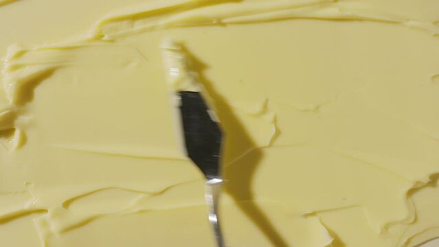 Top view extreme close-up shot of yellow cosmetic cream with turmeric powder are being smeared by palette knife | Cosmetic cream commercial