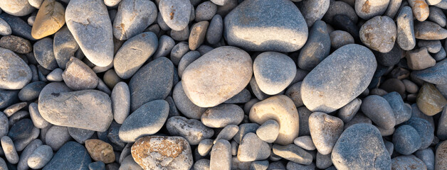 Pebbles on Penmon Beach, Textures.  Varying sizes of pebbles lit with the morning sun.  Grey, blues and yellows