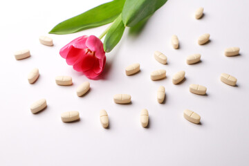 Vitamins pills on a white background and tulips
