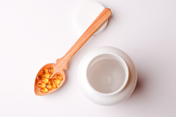 Vitamins pills in a spoon on a white background