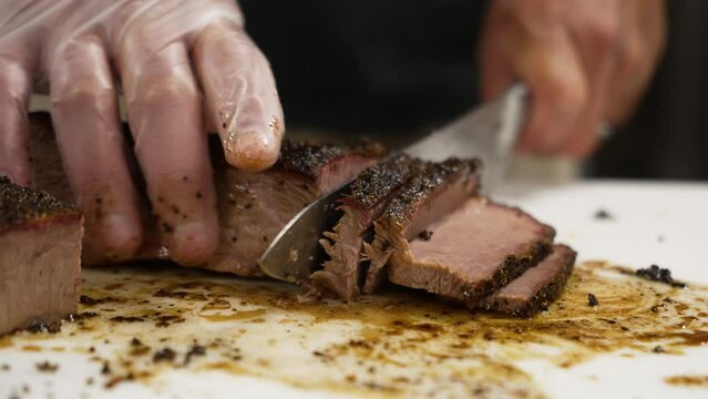Man slices through very lean Texas smoked beef brisket on messy cutting board, slow motion close up 4K