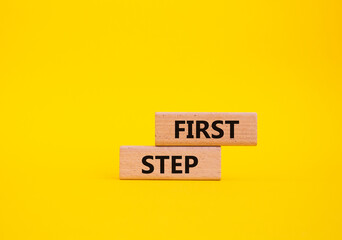 First step symbol. Wooden blocks with words First step. Beautiful yellow background. Business and First step concept. Copy space.