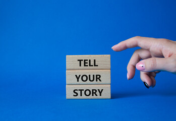 Tell your story symbol. Wooden blocks with words Tell your story. Beautiful blue background. Businessman hand. Business and Tell your story concept. Copy space.