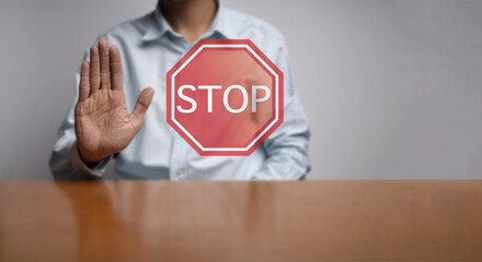 A man put hand to show symbol of stop. Stop sign is in font of palm with background of a man in blue shirt. - 571553813
