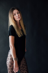 a woman in a black swimsuit bodysuit poses on a black background