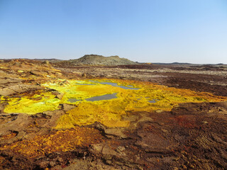 Surreal red and yellow mineral formation with blue pond at Danakil Depression with strong colours in Ethiopia, Africa