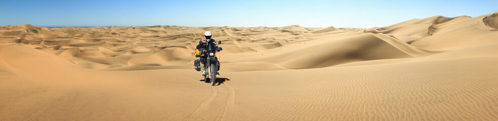 Fototapeta na wymiar One Motorbiker driving in sand dune desert. Motorcycle Adventure in Namib Desert, Namibia.