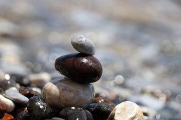 Tower of pebble stones on blurred background of sea waves. Beach vacation, balance and relax concept