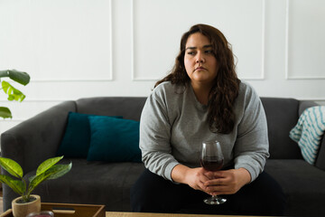 Sad obese woman drinking wine looking lonely