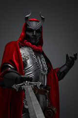 Naklejka premium Portrait of evil knight with black mask pointing his sword to camera.