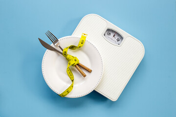 Weight scale and tape measure on dinner plate. Dieting and weight control concept