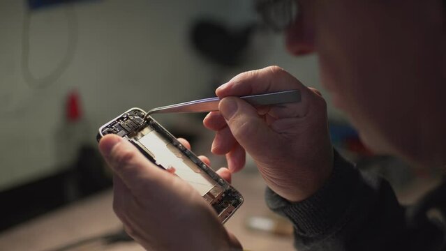 an adult man in the workshop repairs a smartphone. close-up. High-quality shooting in 4k format