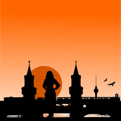 Silhouette: Frau blickt bei Sonnenuntergang auf die Oberbaumbrücke in Berlin - obrazy, fototapety, plakaty