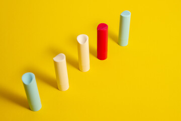 Row Multi-colored tubes of lipstick on a yellow background in an abstract form and shape