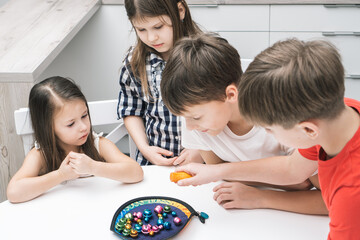 Group of friends play toy fishing on table. Hand of child hold fishing rod and pick up colorful metal playthings from plate. Home leisure, funny playtime. Entertaining interesting board game.