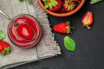 Jar of strawberry jam on dark background. Homemade strawberry marmelade and fruits. Long banner...