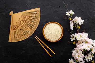 Asian table setting - rice bowl with cherry branch and fan. Top view
