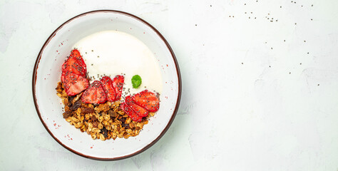 Granola with yogurt with fresh strawberry, chia seeds and honey on a white background. Delicious...