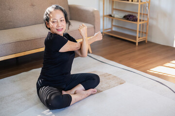 Asian elderly woman meditating practicing yoga for good health At an older age, it's about taking care of your body's health at home on a relaxing day. good health concept