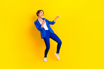 Fototapeta na wymiar Full length photo of excited pretty woman wear blue jacket looking pointing two fingers empty space isolated yellow color background