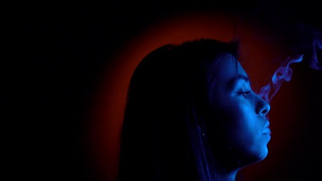 Woman smoke cigarette, side face view with blue lights, bad habits