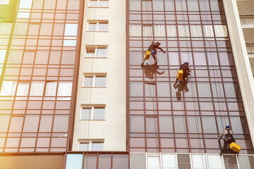 Industry mountaineering workers hangs on residential facade building. Rope access laborers on wall...