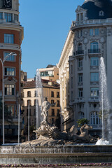 Neptune working fountain on the streets of Madrid. Old historical buildings street view on a sunny day.