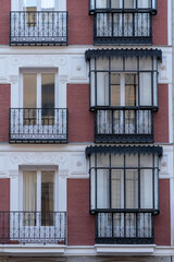 Symmetrical white and brown facade of an old house in Madrid with windows and balconies.
