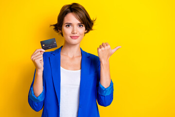 Photo of young promoter beautiful lady wear trendy outfit hold debit card save money direct thumb mockup banking isolated on yellow color background - obrazy, fototapety, plakaty