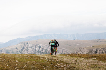 Obraz na płótnie Canvas back two cyclists riding on mountain road on mountain bike