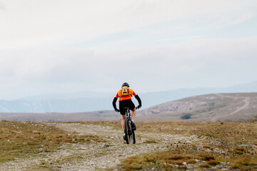 lone male cyclist riding on mountain road with backpack