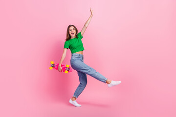 Full length photo of excited sweet girl wear green crop top riding skate walking empty space isolated pink color background