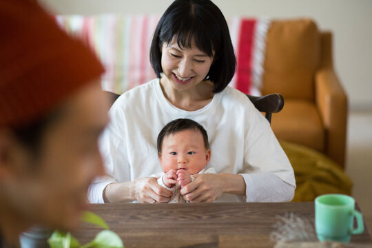 あかちゃんを膝の上に座らせている母親と手前に座る父親