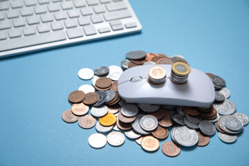 Computer mouse and coins on the blue background.