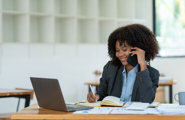 Young african american businesswoman sitting at the table in the office while making with a business colleague in receiving good news on modern business contracts.