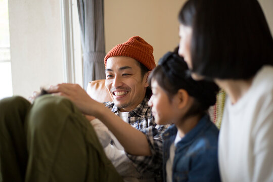 あかちゃんを膝の上に乗せてあやす父親とそれを見守る小学生の姉と母親
