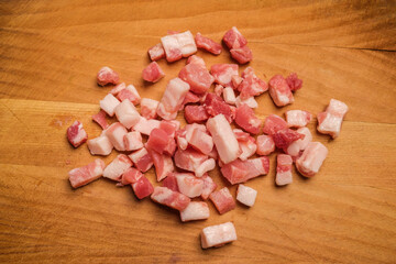 Diced Bacon on a wooden cutting board, close up.