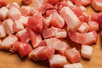 Diced Bacon on a wooden cutting board, close up.