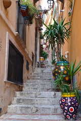 colorful painted vases and flower pots on narrow stairs in the old town of Taormina, Sicily        ...