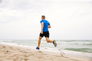 back male runner athlete run on sandy beach