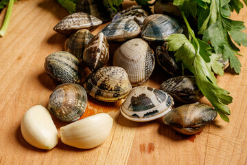 Close up of a cutting board with garlic clams and parsley, typical ingredients of pasta with clams